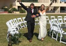 A beautiful bride and charming groom pose for the camera in front of the historic Price Tower.